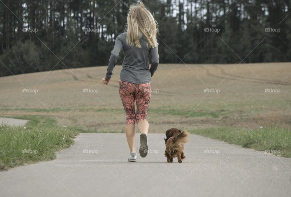 girl running along the road with a dog