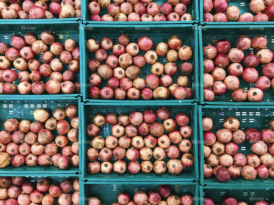 Many red fresh pomegranates in blue boxes for sale 