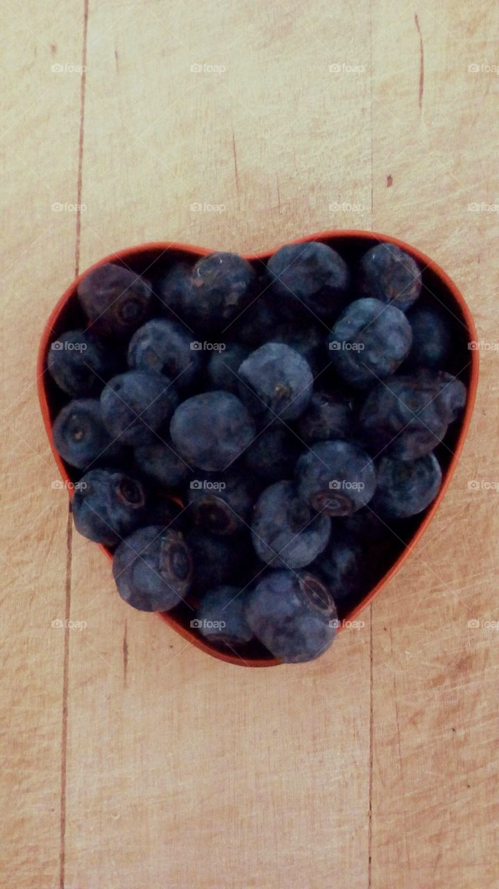 Bowl with  fresh healthy round blueberries
on wooden table/tray
