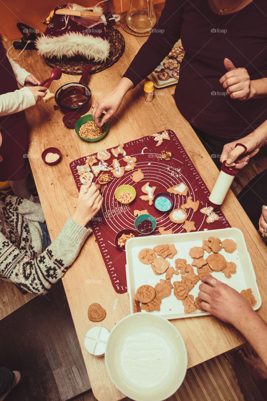 Baking Christmas cookies. Christmas gingerbread cookies in many shapes decorated with colorful frosting, sprinkle, icing, chocolate coating, toppers, put on table. Baking traditional cookies. Family celebrating Christmas. Baking at home