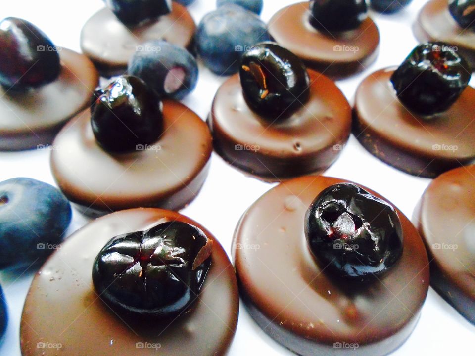 Round pieces of chocolate with blueberries on white background