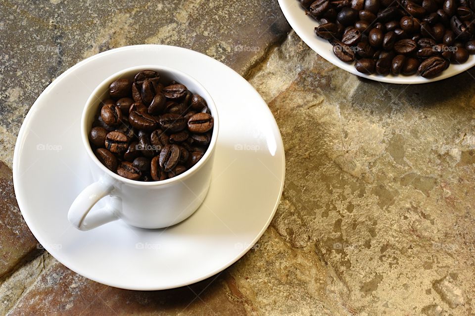 coffee beans in a white cup on stone floor background