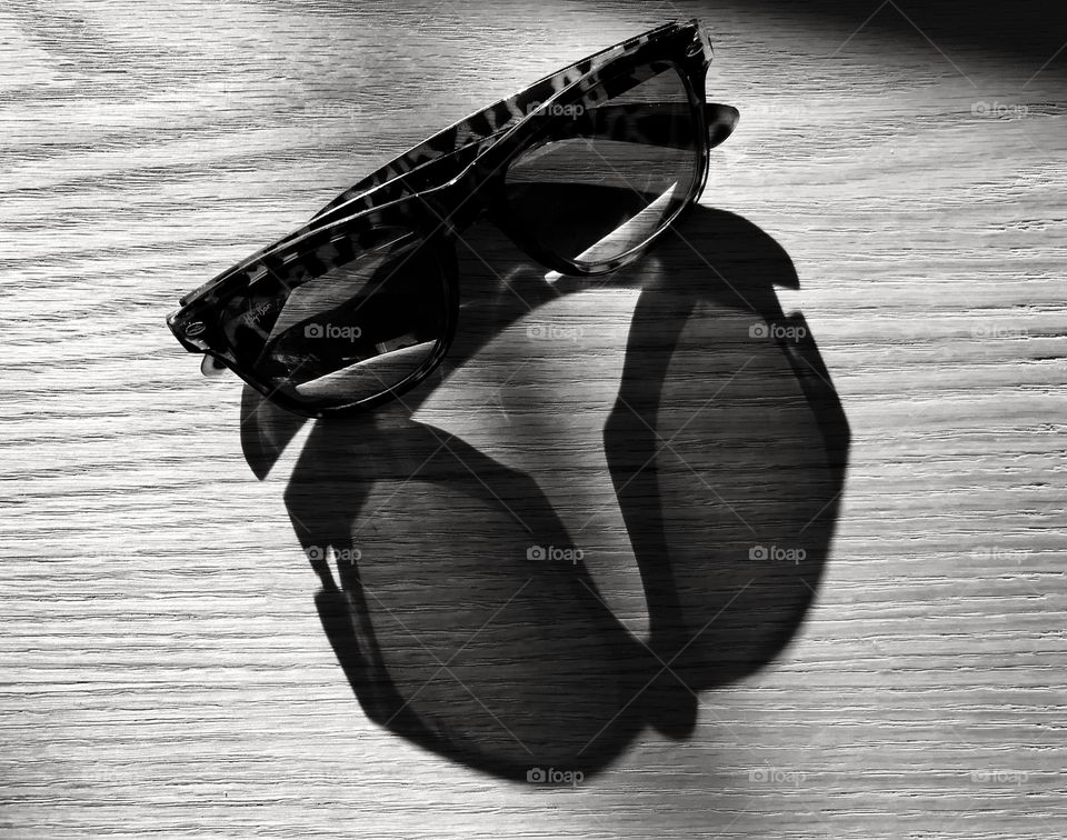 shadow of a dark glasses on a wooden table