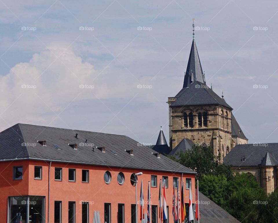 A mauve colored building with lots of windows with older stone architecture in the background on a pleasant summer day in Europe. 