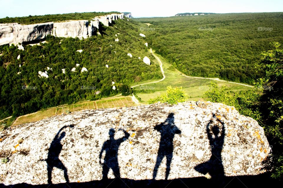 Shadows of heroes on the stone of the ancient cave city in the Crimea. Travel, become a hero of summer adventures.