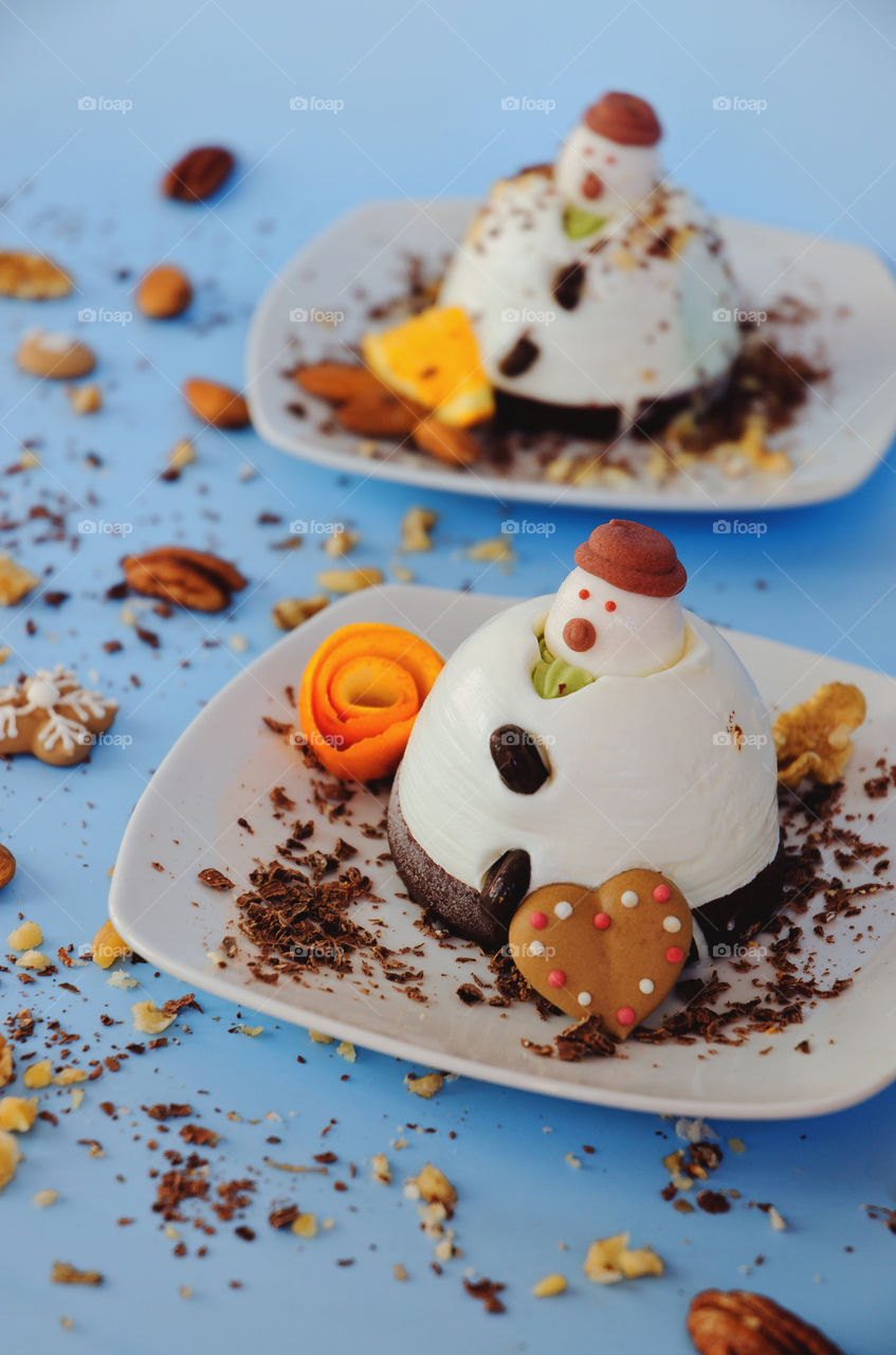 Ice cream background in the shape of two edible snowmen on white plates close up. Top view. Funny food idea for kids.