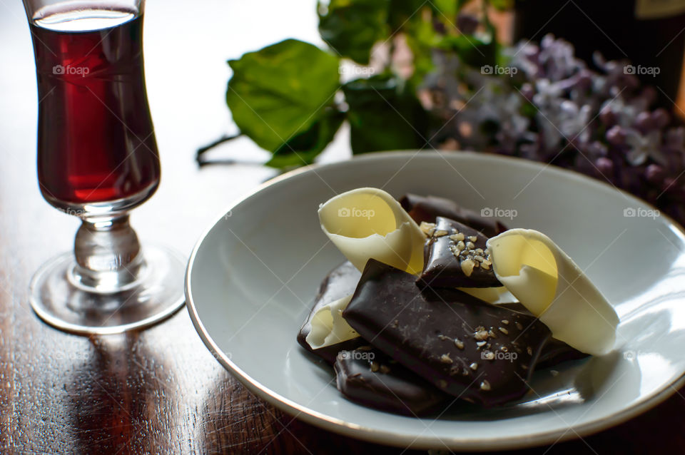 Pieces of dark chocolate toffee with salted caramel on plate next to port wine 