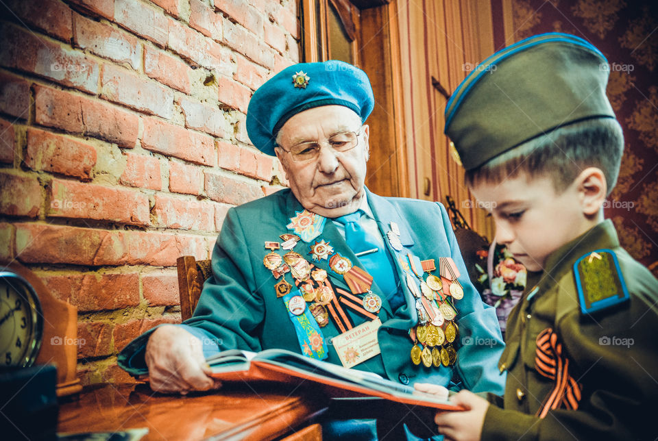 ветеран  второй мировой войны с внуком смотрит фотоальбом