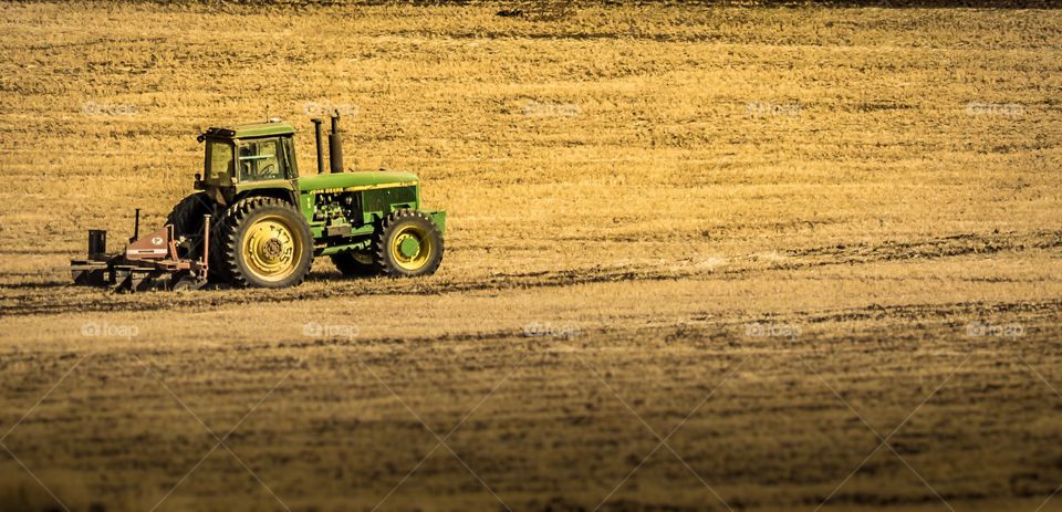 Farmer working his field with a John Deere tractor in the fall.   