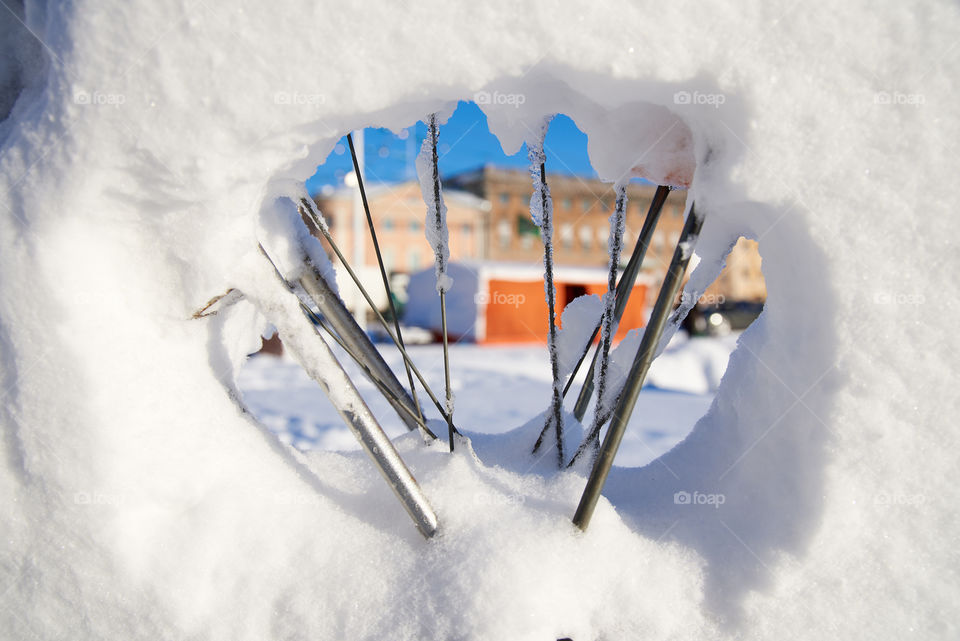 Market stalls at Kauppatori in Helsinki, Finland seen through bicycle and its spokes covered with snow.