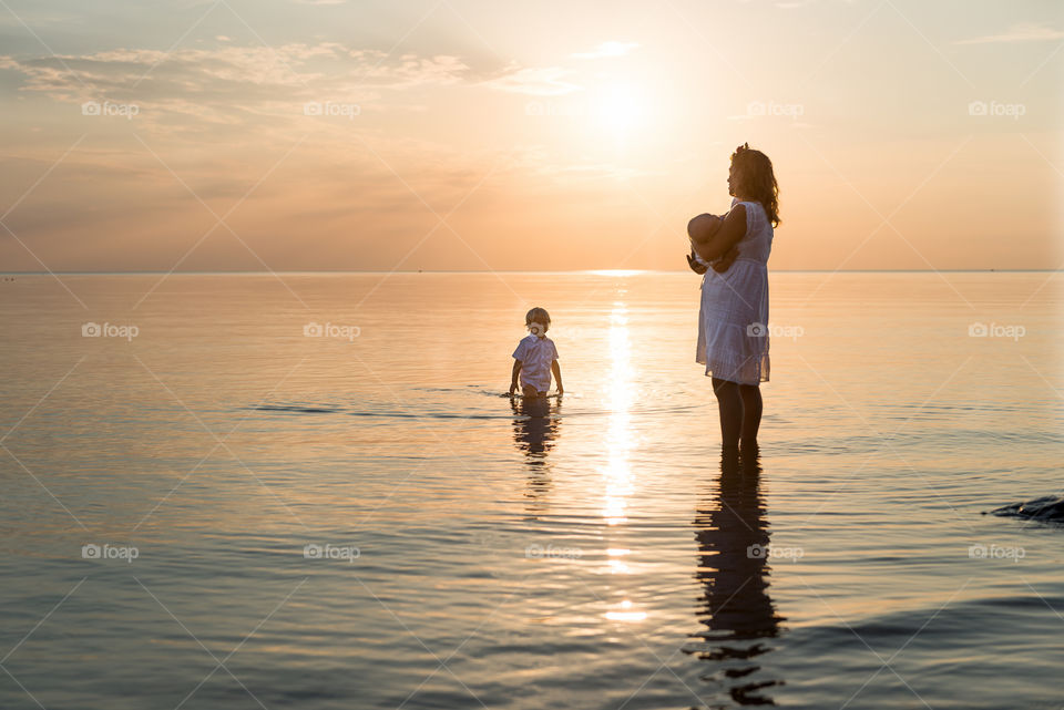 Mother with two children on the beach at sunset