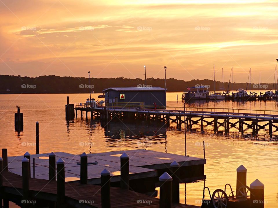 This dramatic sunset happened right after a rainstorm. Golden colored clouds reflect  on the surface as sailboats sit idle