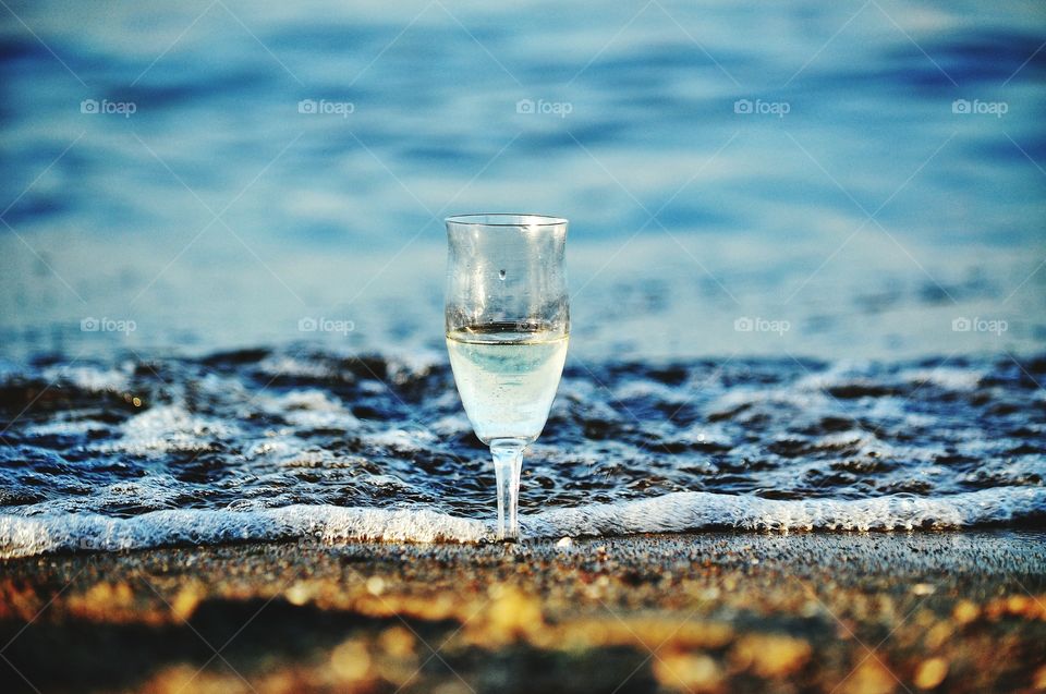 wine glass on the beach with sea wave