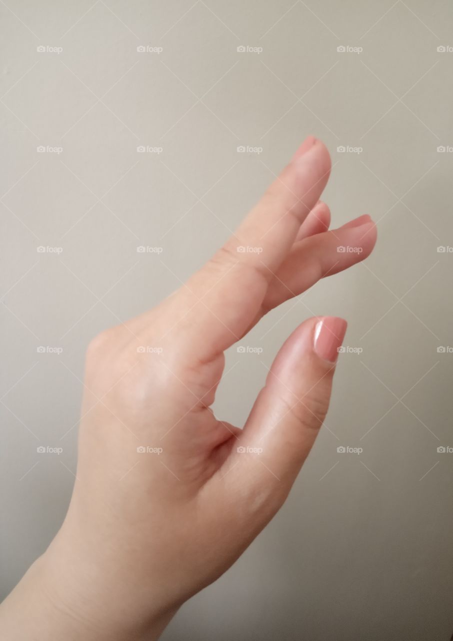 Women soft skin hand, with glossy nude nail polish.