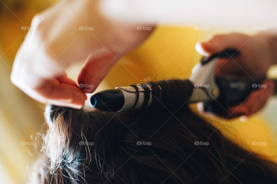 Hairdresser making curls using tong machine