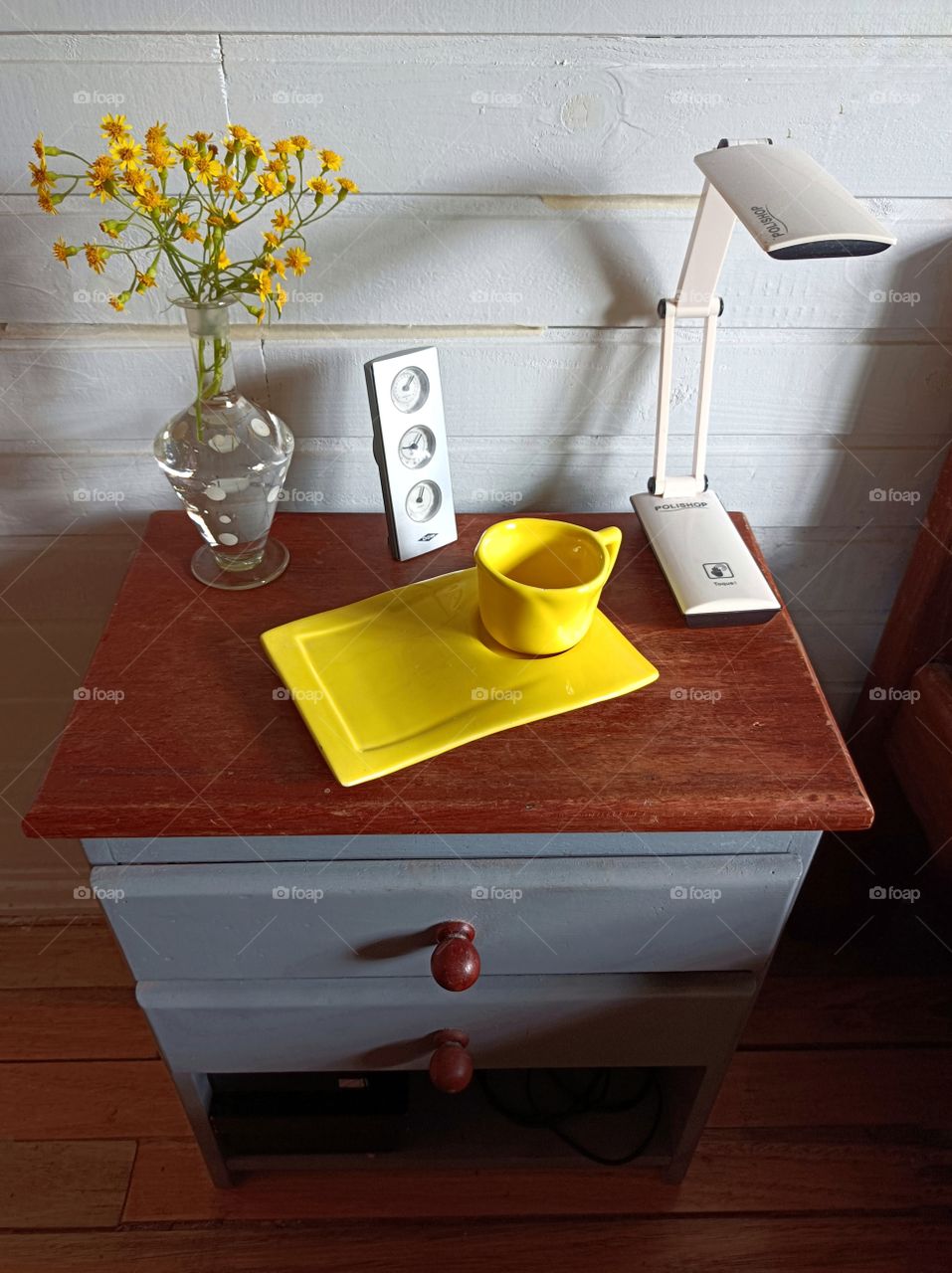 Gray bedside table and yellow cup with vase and yellow flowers