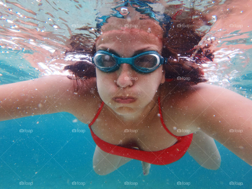 woman with goggles underwater. woman wearing goggles underwater holding breath