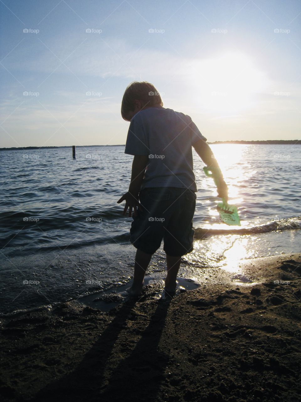 Gorgeous photo of young boy playing in the sand at the beach during a beautiful sunset!! 