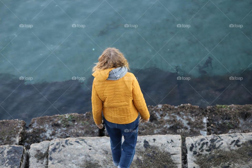 Woman with yellow jacket  by the ocean 