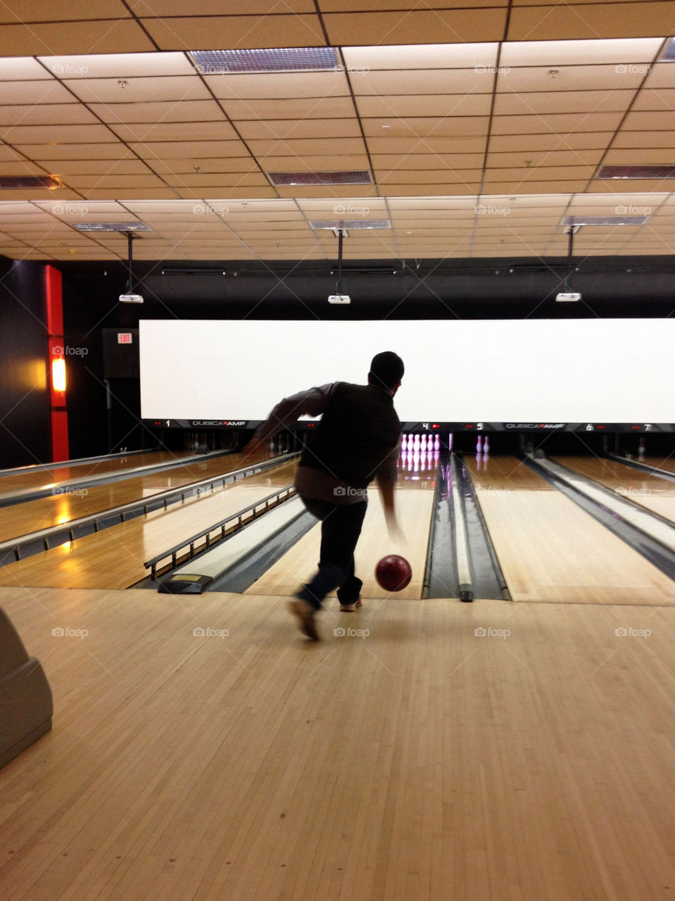 Silhouette from behind of a man bowling