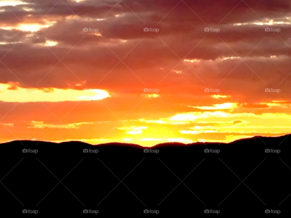 A golden sunset descending over the silhouetted Blue Ridge Mountains. 