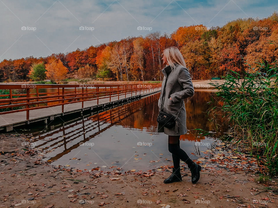 Girl walks by the river in the autumn forest