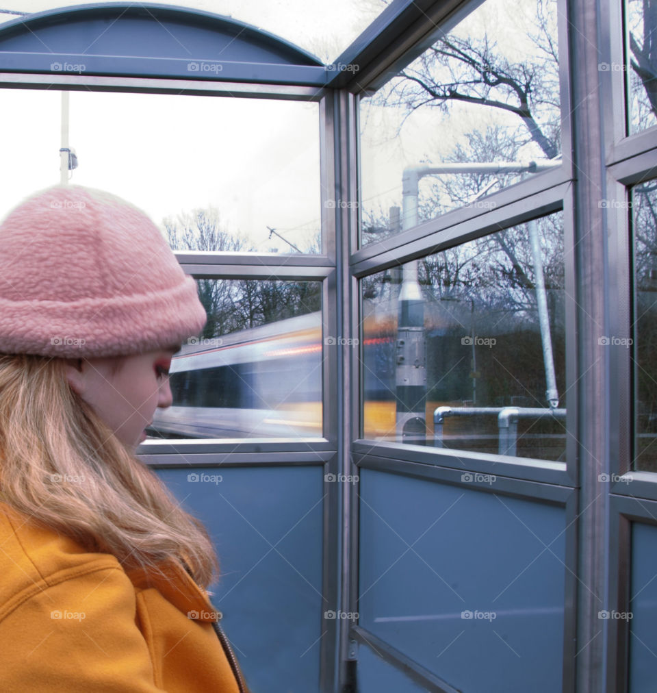 A girl waiting for a train at the station, with a motion capture of a train rushing past. 