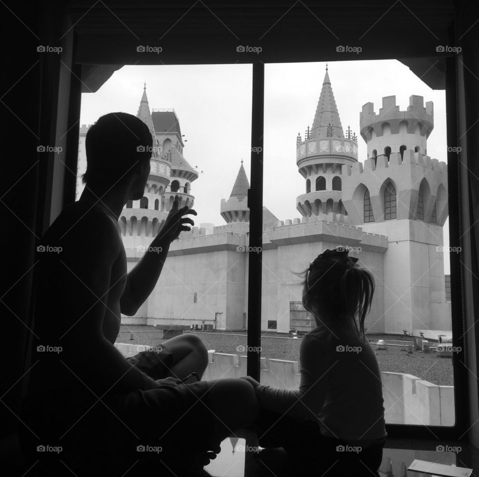 Father pointing church and sitting on window with daughter