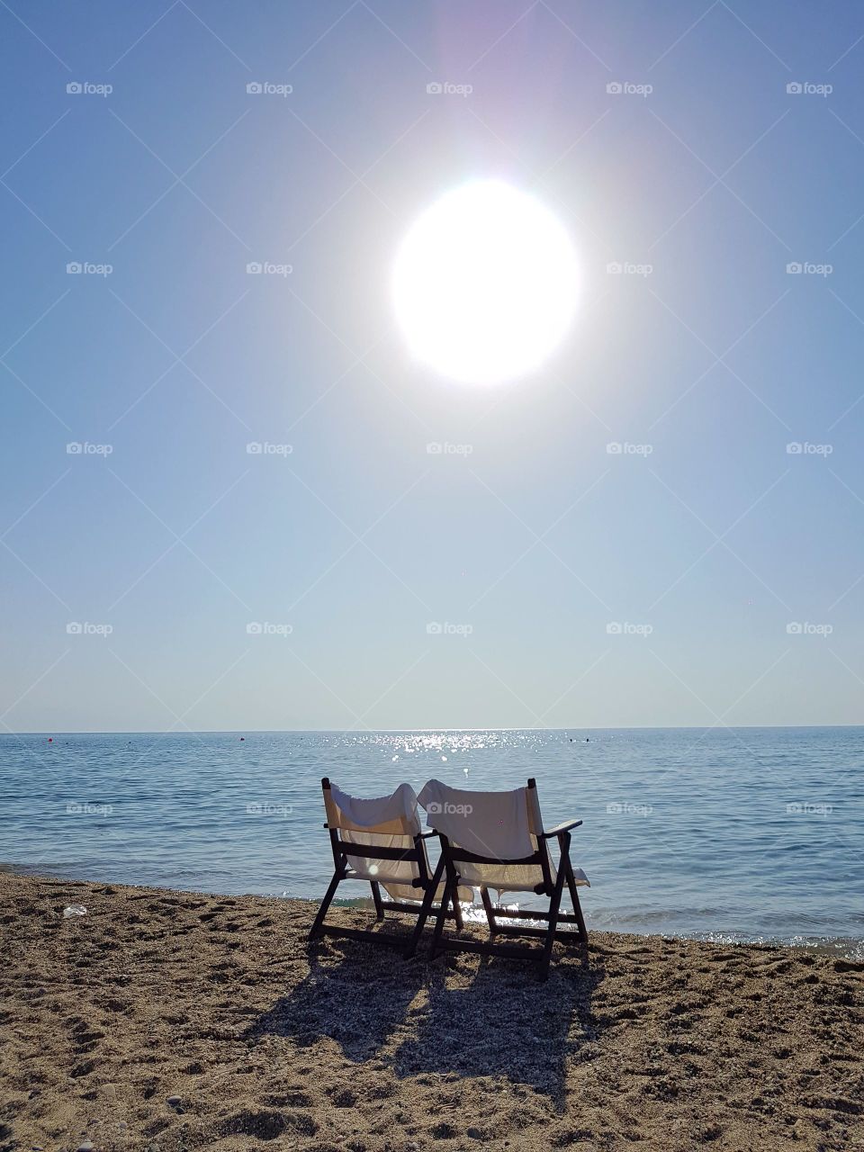 two empty chairs sunny sandy beach