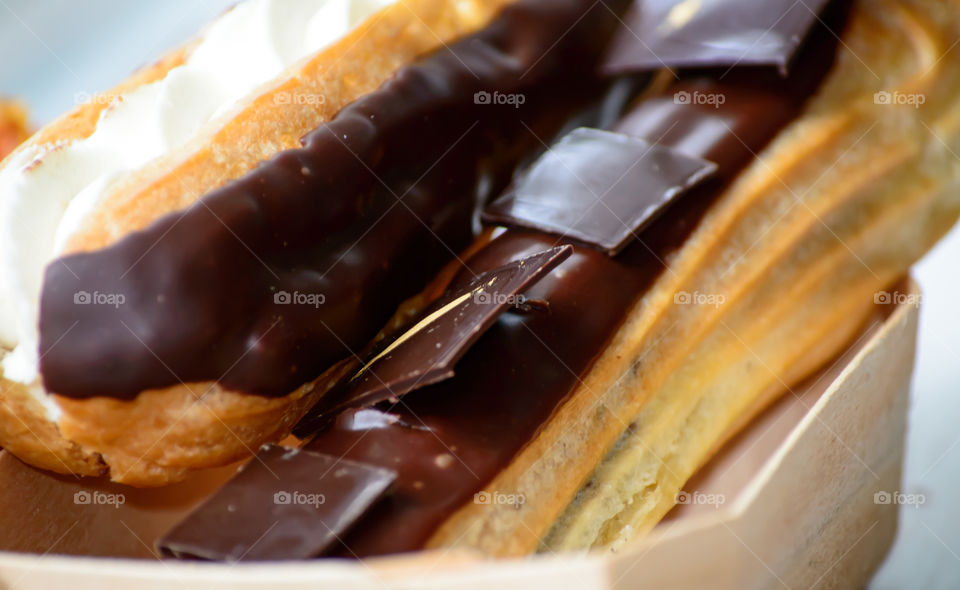 Closeup dark chocolate decorated with gold in square shape on chocolate ganache covering puff pastry with whipped cream closeup 