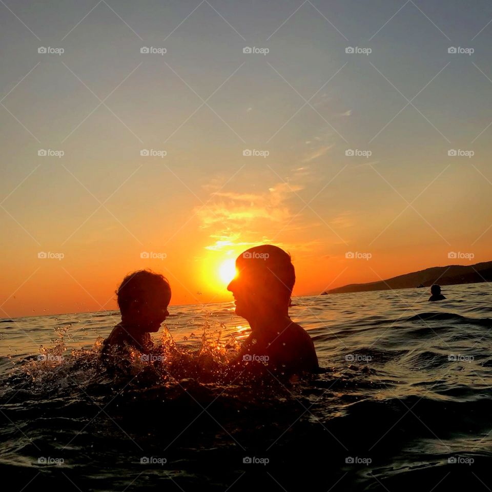 Отец и сын веселятся на закате