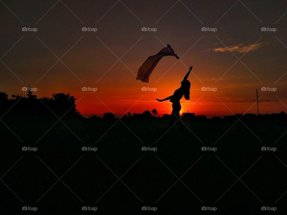 Woman silhouette on sunset background