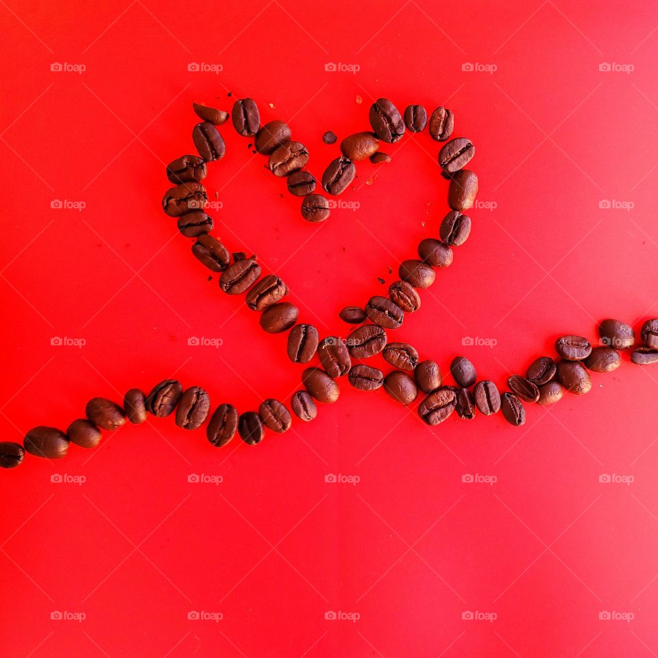 Coffee beans in a heart shape with a red background