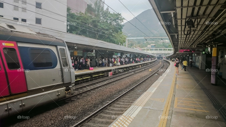 Crowded Train Platform in Hong Kong. A MTR train arrives to a crowded platform at Kowloon Tong Station on a smoggy Hong Kong day.