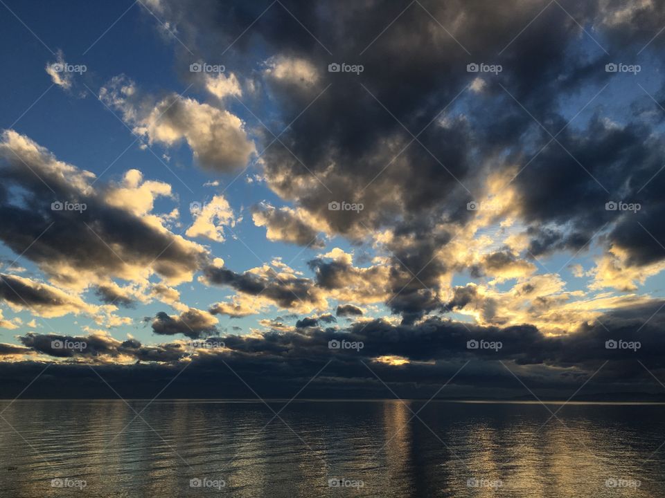 Scenic view of sea against cloudy sky at sunset