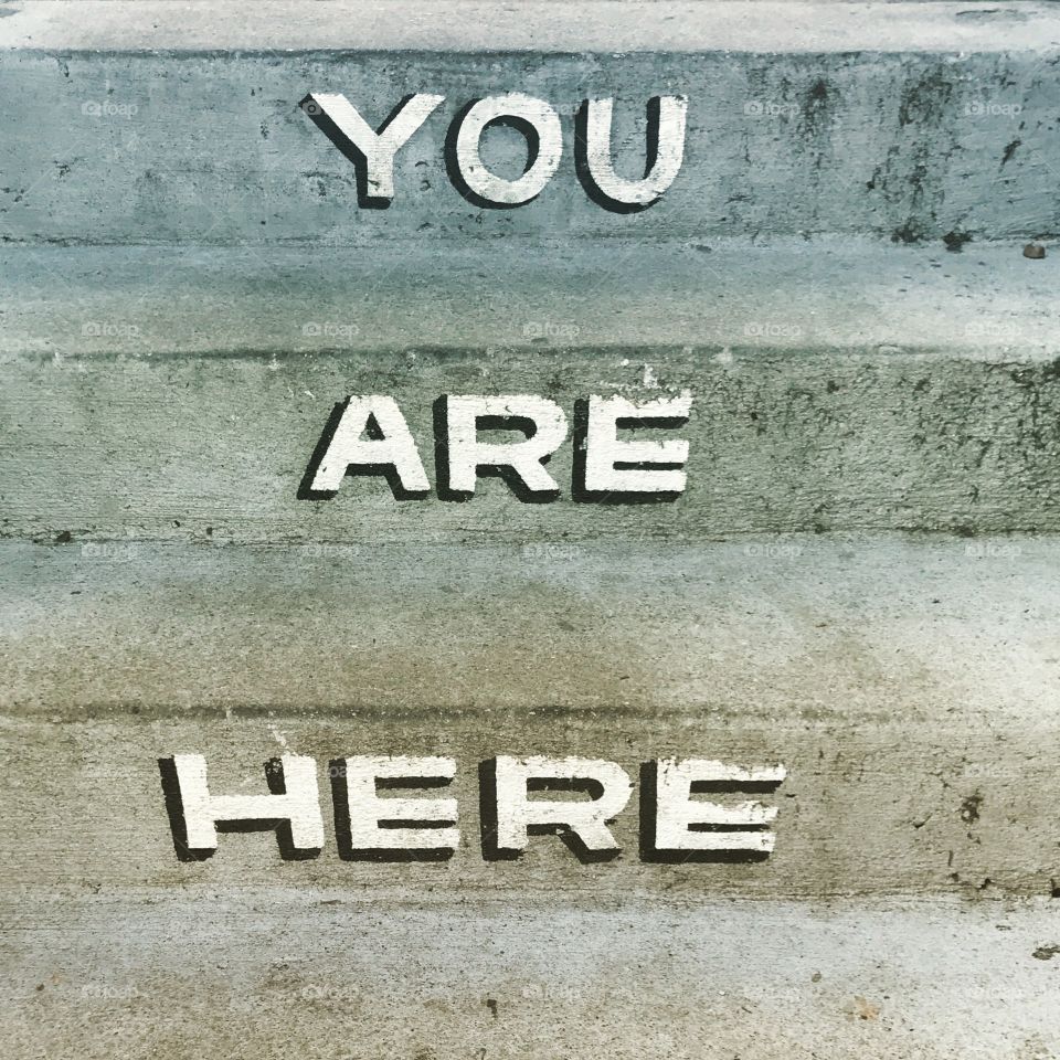 The message ‘you are here’ painted onto concrete steps
