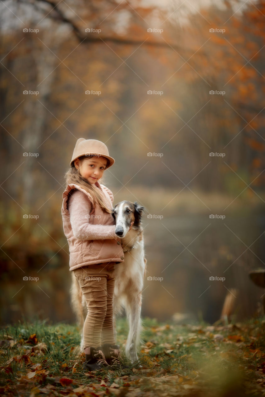 Cute smiling girl with borzoi dog in an autumn park 