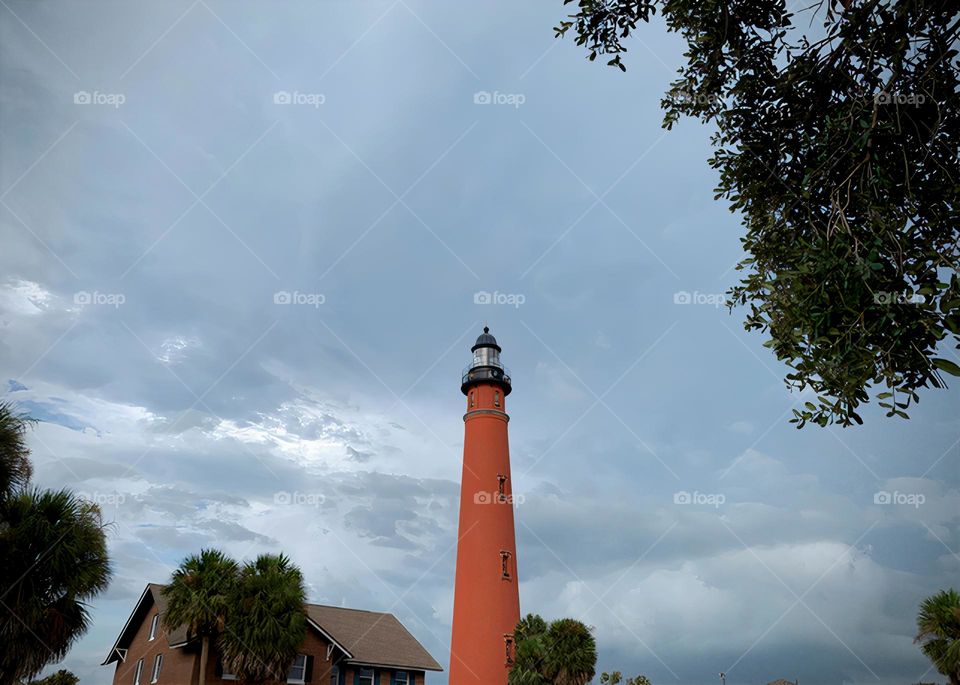 Ponce Inlet Lighthouse, also called the Mosquito Inlet Lighthouse, with brown farm house style museum store. The current tower was lit in 1887 and stands 175 feet tall, making it the tallest lighthouse in Florida, third in the USA.