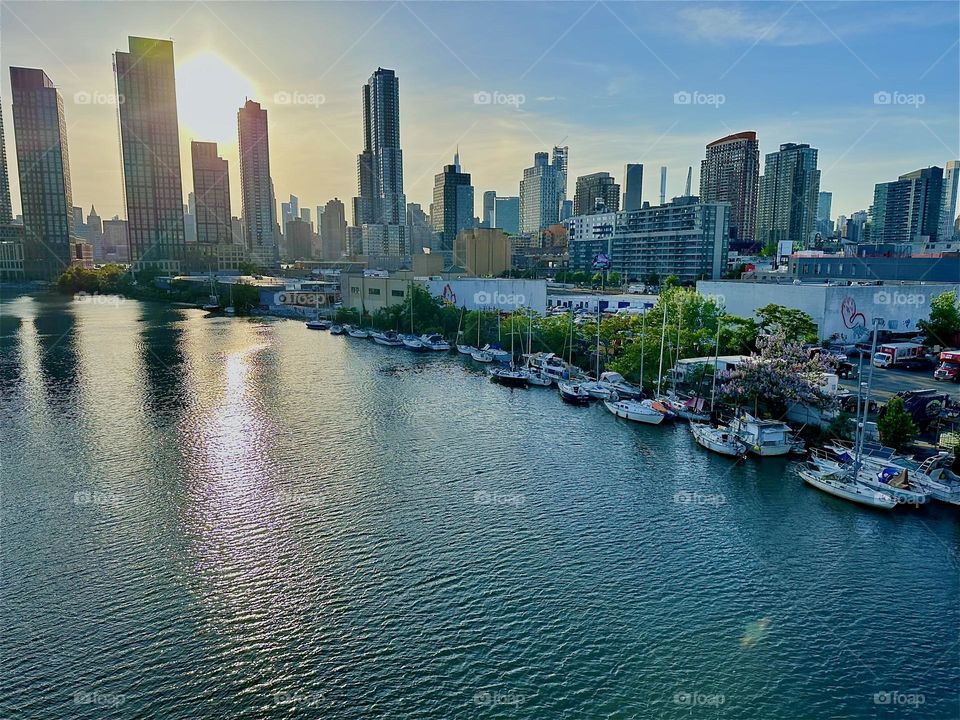 This is “Newtown Creek” seen from the “Pulaski Bridge” that connects “Greenpoint”, Brooklyn to LIC, Queens at sunset time. Across the water of the “East River” in the distance we see “Manhattan”. 2024. Hypnotic Productions