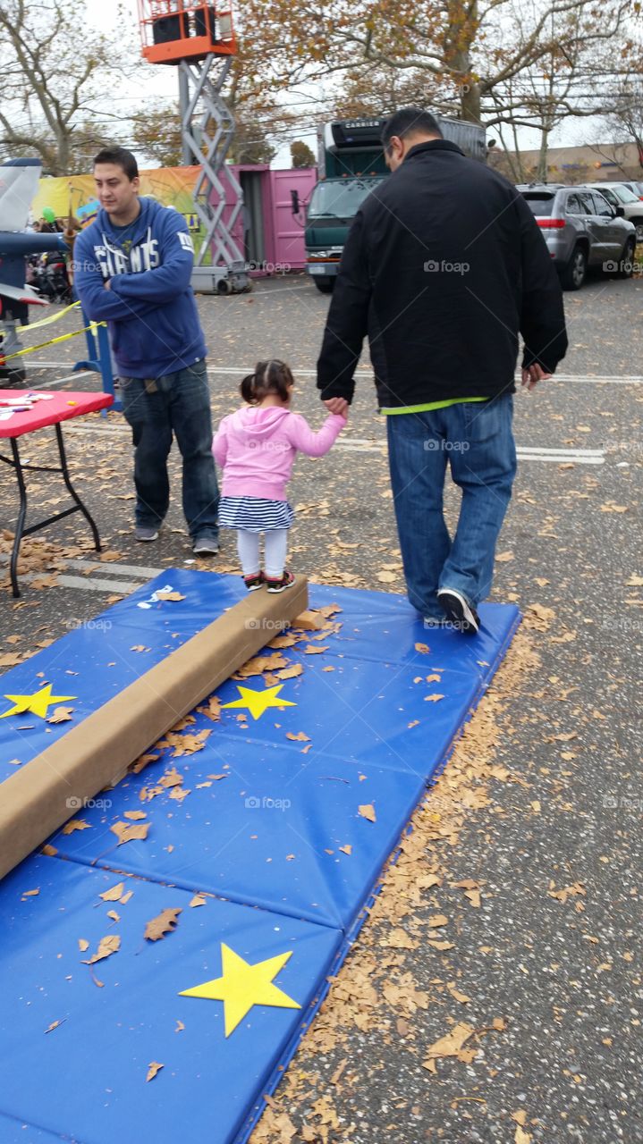 daddy helping his daughter across a balance beam