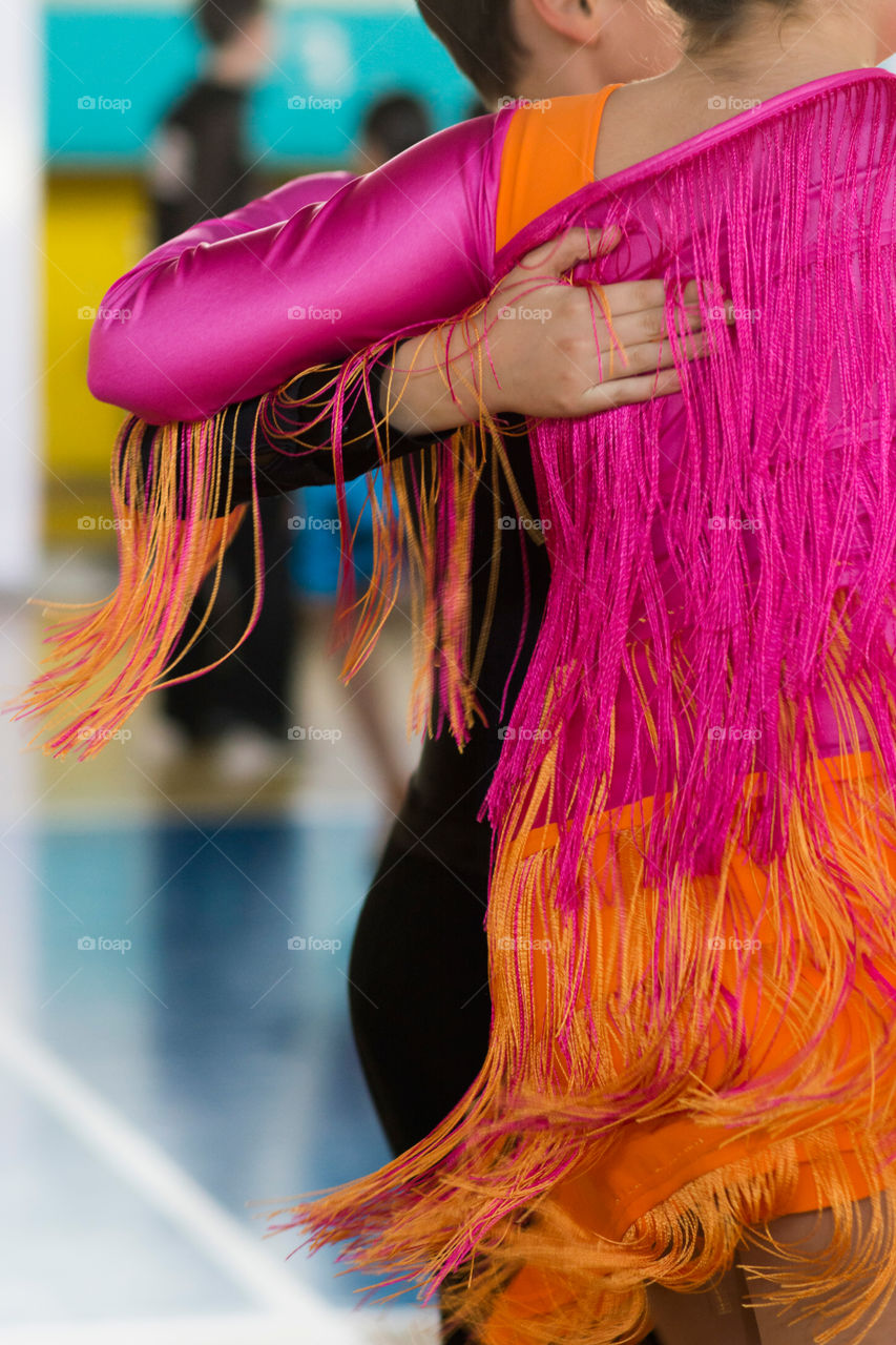 Close up of a girl wearing fringes colorful dress in latino dancing competition