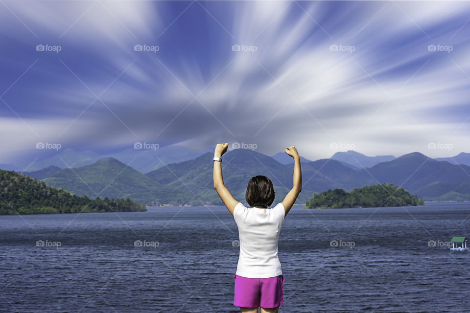 Women raise their arms at Kaeng Krachan Dam phetchaburi in Thailand and the clouds are flowing.