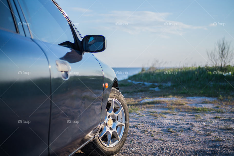 The car stands on the seashore at sunset