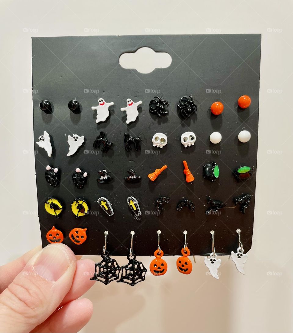 Woman holds Halloween earrings, card full of Halloween earrings, Halloween characters 