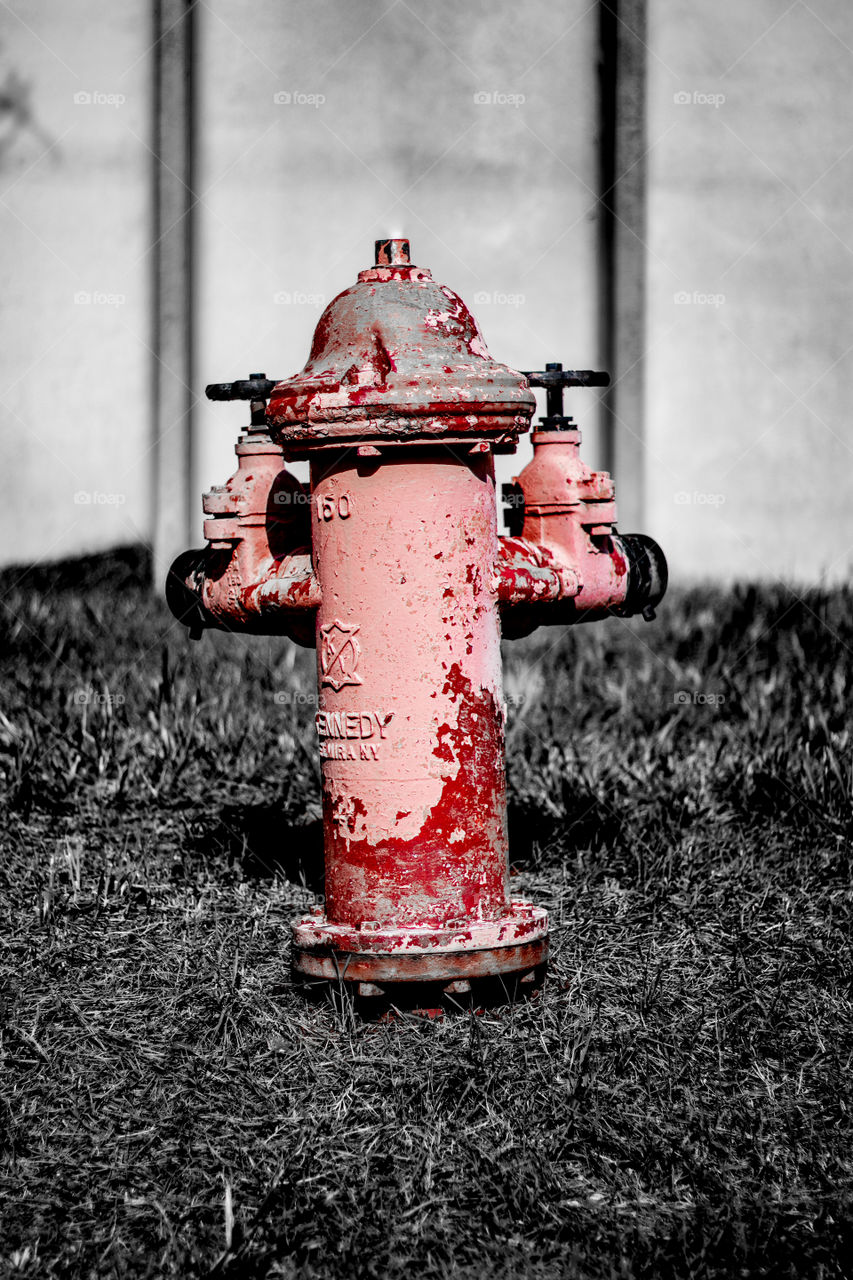 A paint peeling, rusty fire hydrant found in a quiet industrial park
