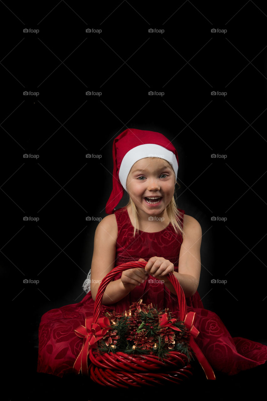 Four year old girl posing in santa dress for christmas.