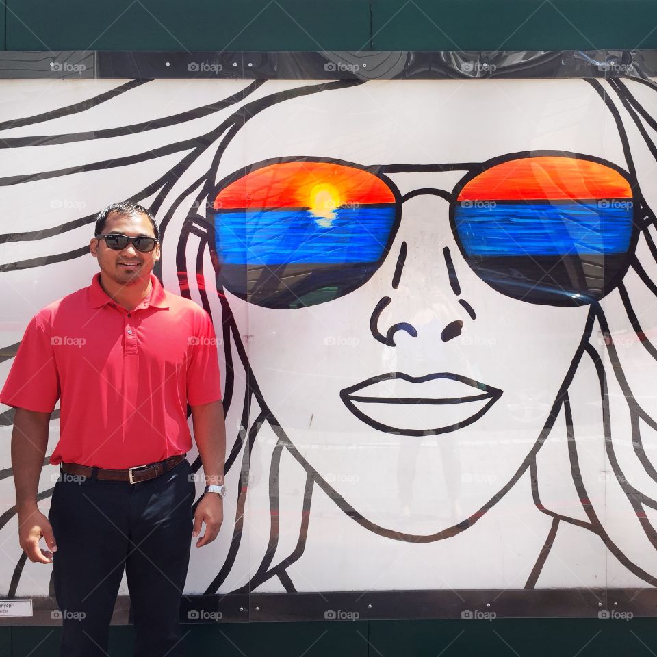 New Summer shades. Man with sunglasses posing against sunglass street art.