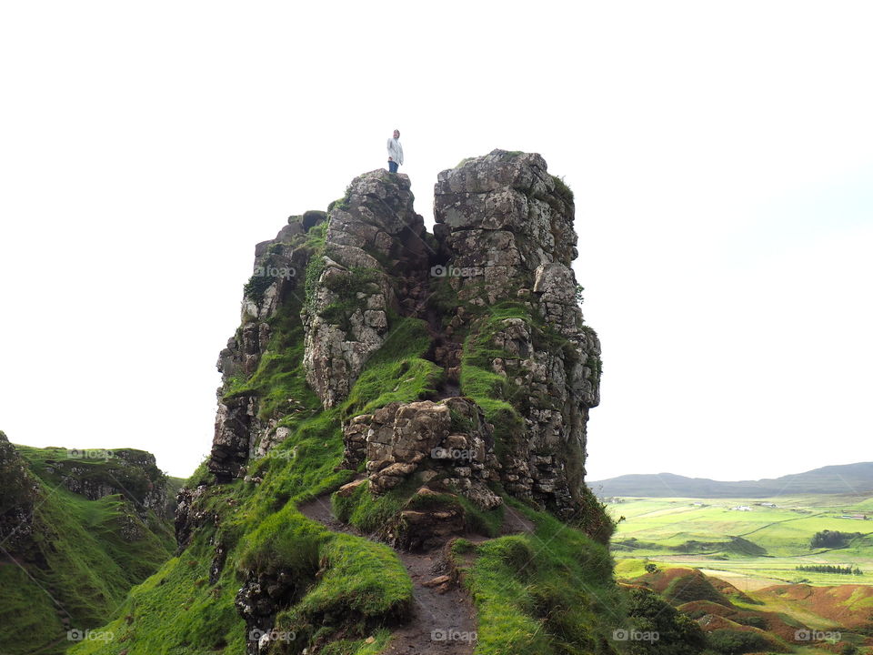 Hiker on the top of a hill at the fairy glen near uig, Isle of Skye in Scotland with bright green grass on a typical Scottish autumn day.