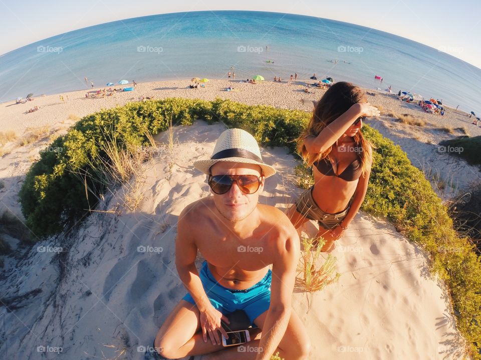 Fish eye lens view of man and woman sitting at beach