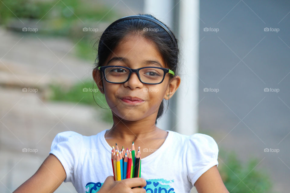 Smiling girl holding bunch of color pencil